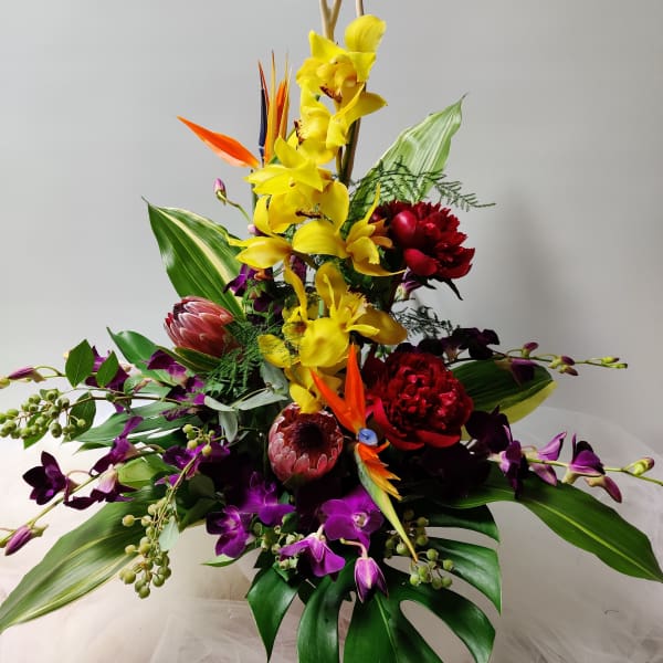 Tropical bouquet with yellow orchids, purple orchids, and red blooms
