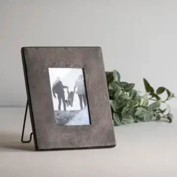 Wooden photo frame with greenery behind it