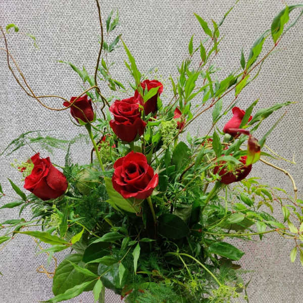 Red roses in a clear glass vase with airy greenery