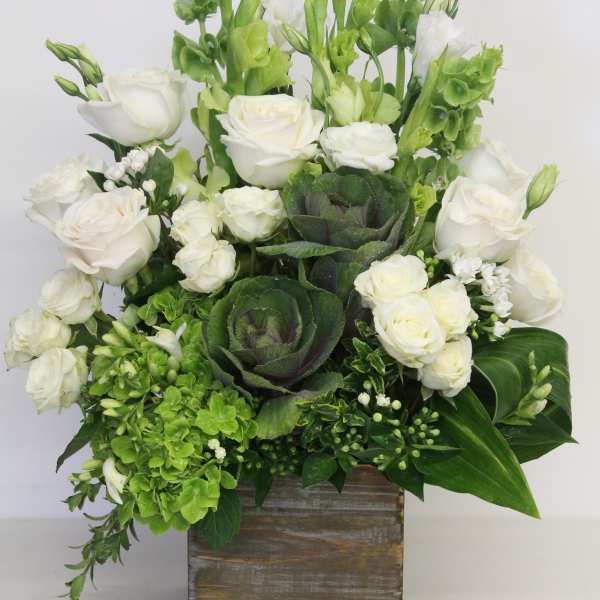 White rose arrangement with green bells of Ireland and ornamental cabbage in a rustic wooden box