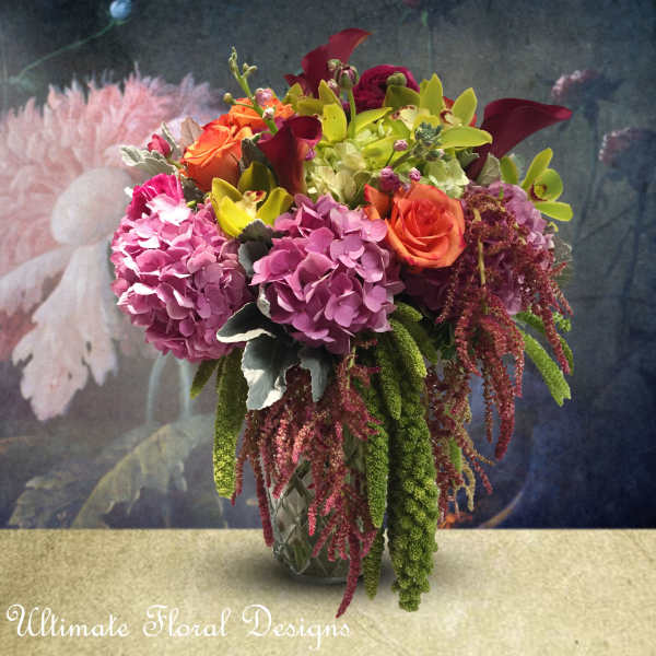 Colorful bouquet of roses, hydrangeas, and calla lilies in a glass vase