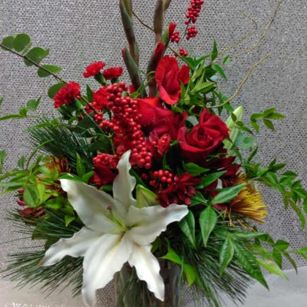 Red roses and white lilies in a glass vase with tall decorative branches