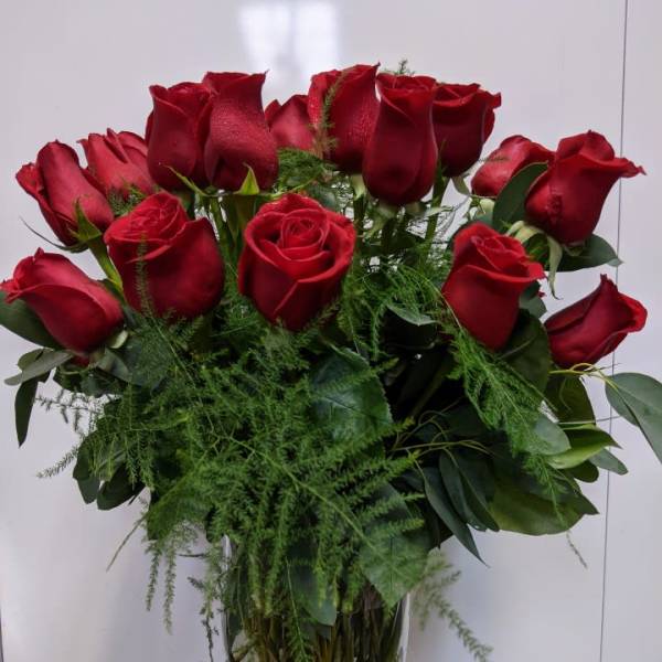 Bouquet of red roses in a glass vase with greenery