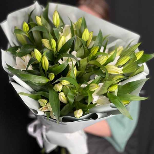 Bouquet of white lilies with yellow buds wrapped in white paper
