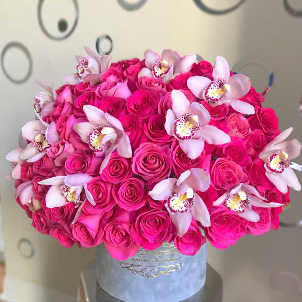Round hatbox arrangement of bright pink roses accented with pale pink orchids