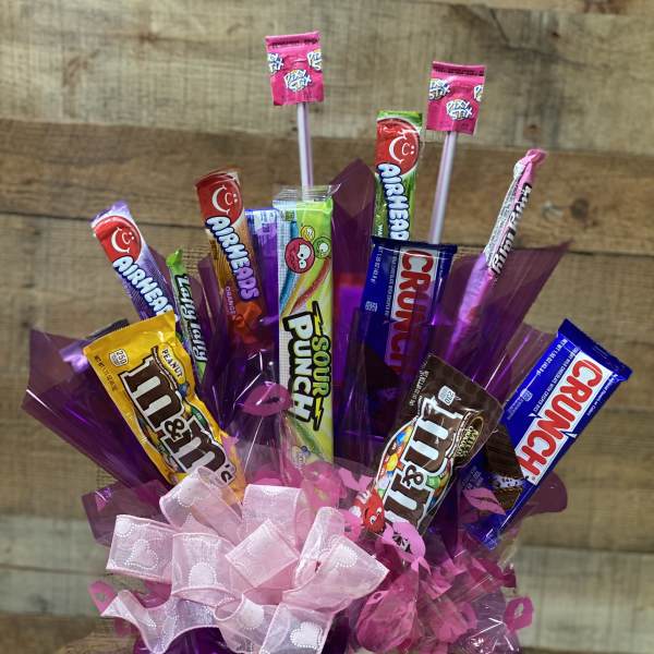Candy bouquet in a pink vase with purple wrapping and a pink bow