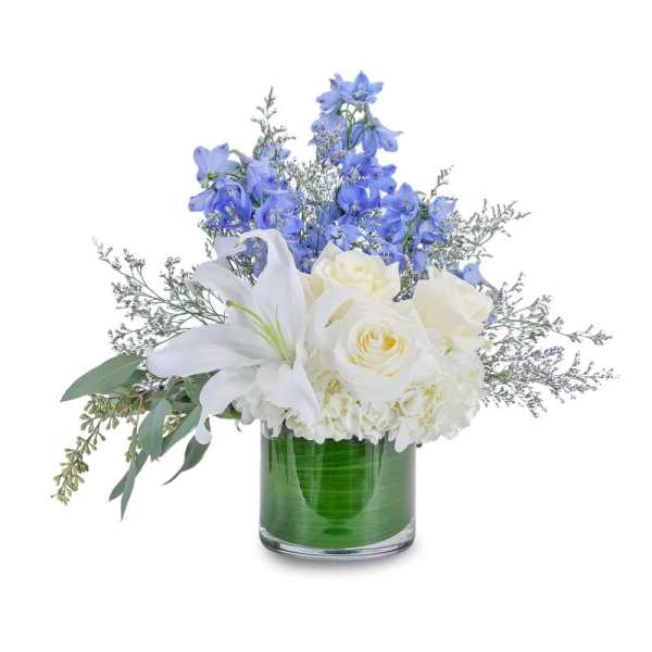 White lilies and roses in a glass vase with blue flowers