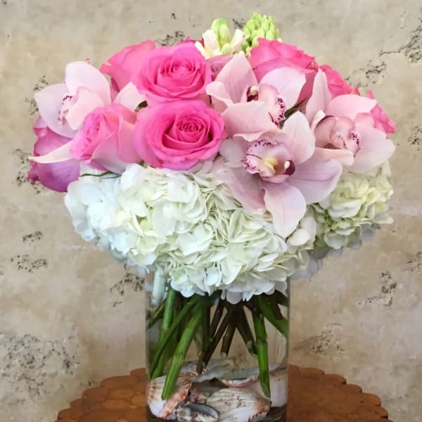Pink roses and pale orchids in a glass vase with white hydrangeas