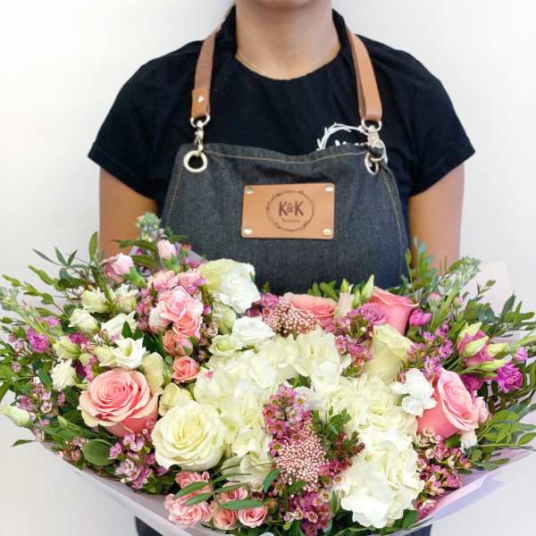 Large bouquet of pink and white roses with hydrangeas held by a florist