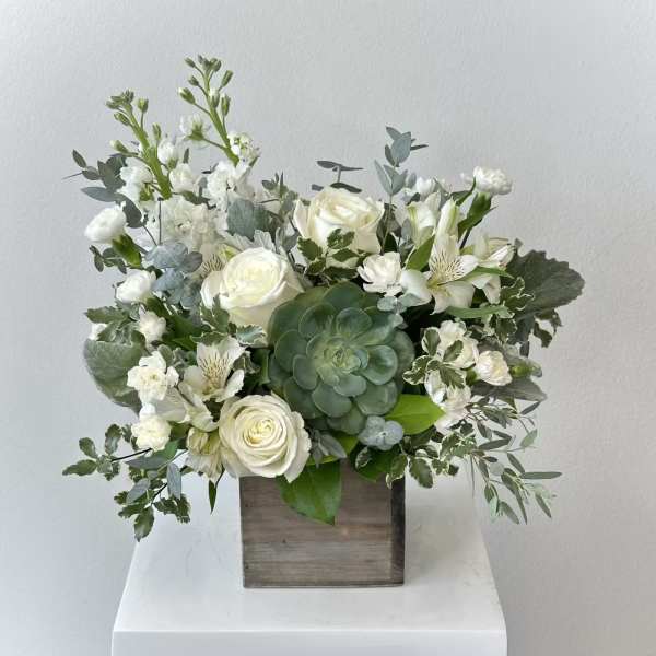 White floral arrangement in a wooden box with a green succulent centerpiece