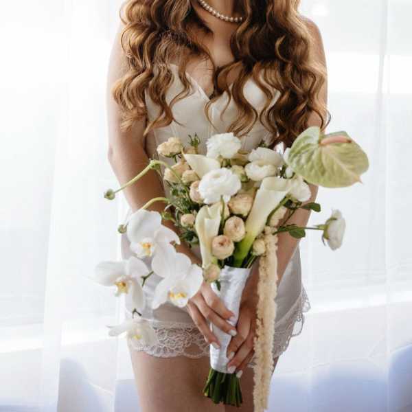 Bride holding a white bouquet with calla lilies and orchids
