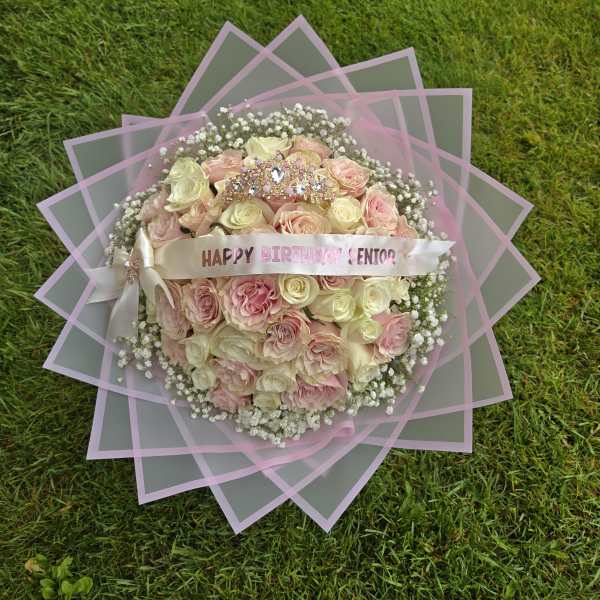 Pink and cream rose bouquet with a birthday ribbon on grass