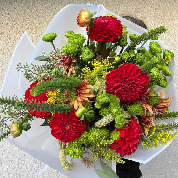 Bouquet of red and green flowers wrapped in white paper