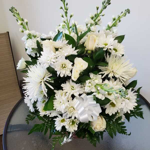White floral arrangement with daisies and roses in a basket