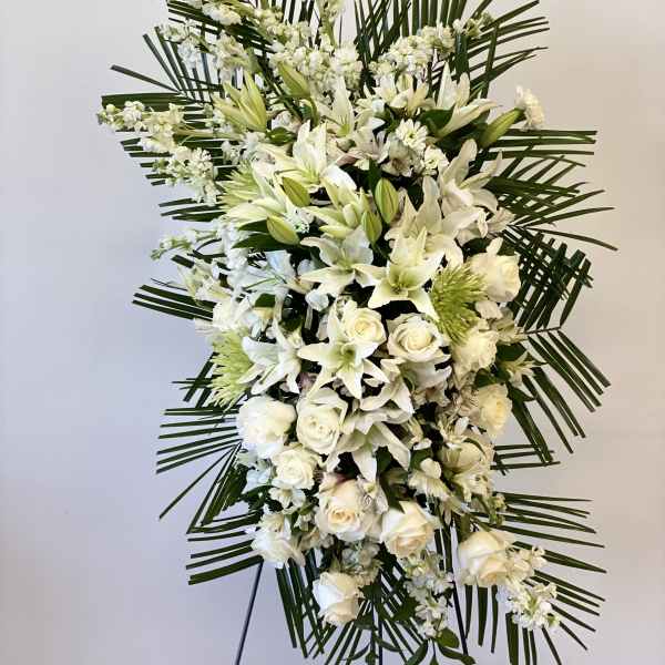 Tall white floral standing spray with roses and lilies on a stand