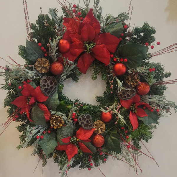 Christmas wreath with red poinsettias, pinecones, and red ornaments