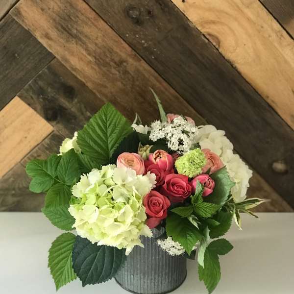 Pink roses and hydrangeas arranged in a metal container