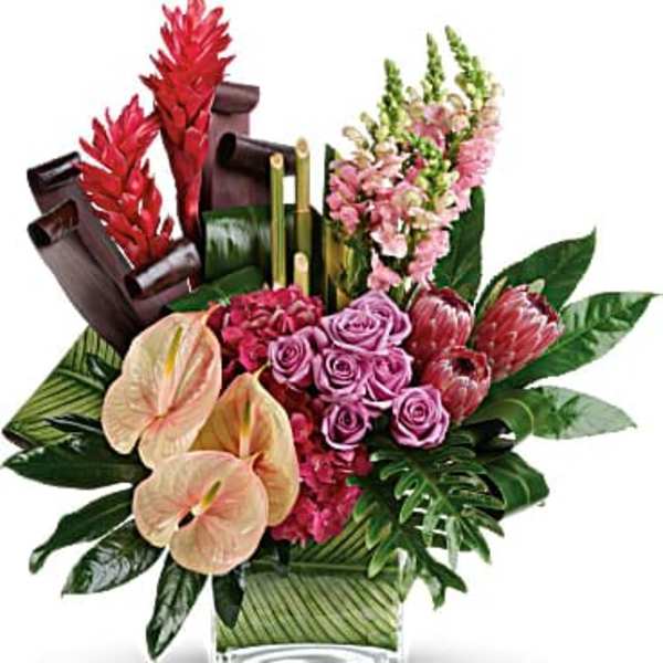 Tropical floral arrangement with pink roses and anthuriums in a glass vase
