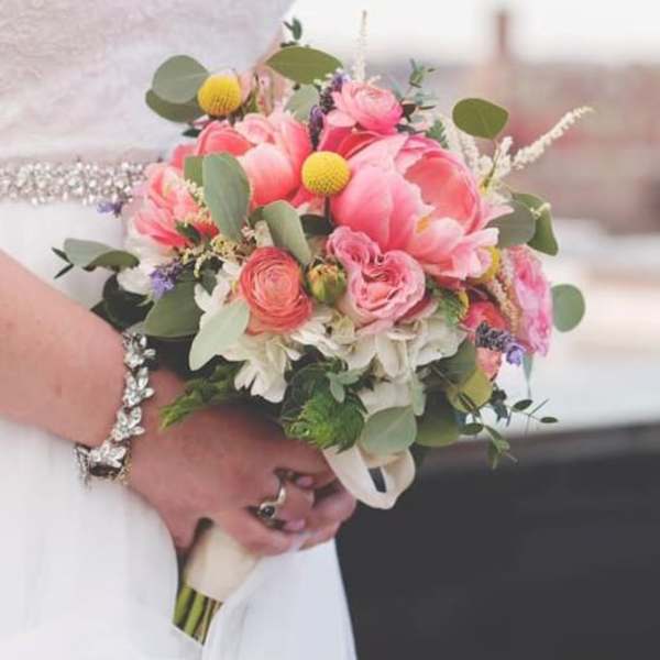 Bride holding a pink and white bouquet with greenery