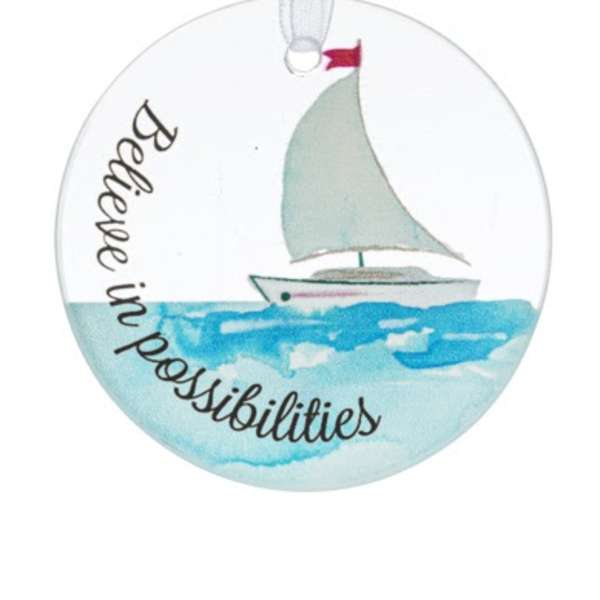 Round ornament with watercolor sailboat on blue water and the phrase 'Believe in possibilities'.