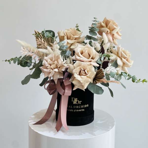 Peach roses in a black hatbox with pink ribbon