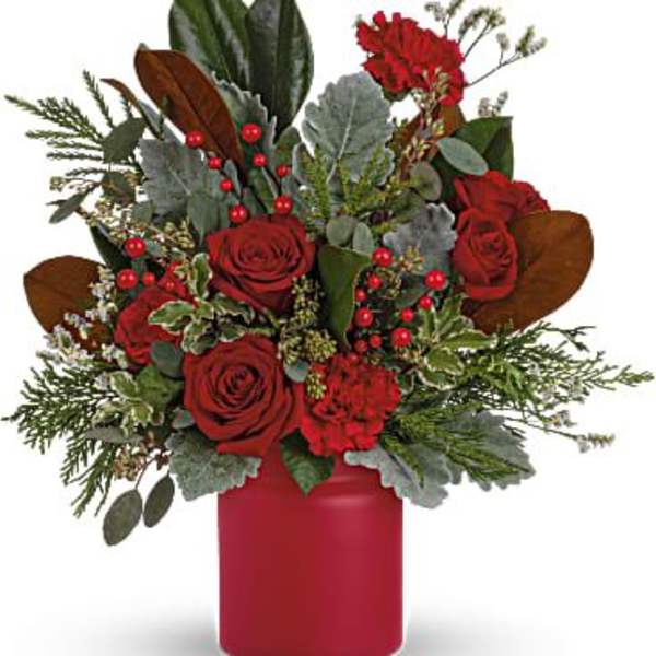 Red roses in a red vase with greenery and berry accents