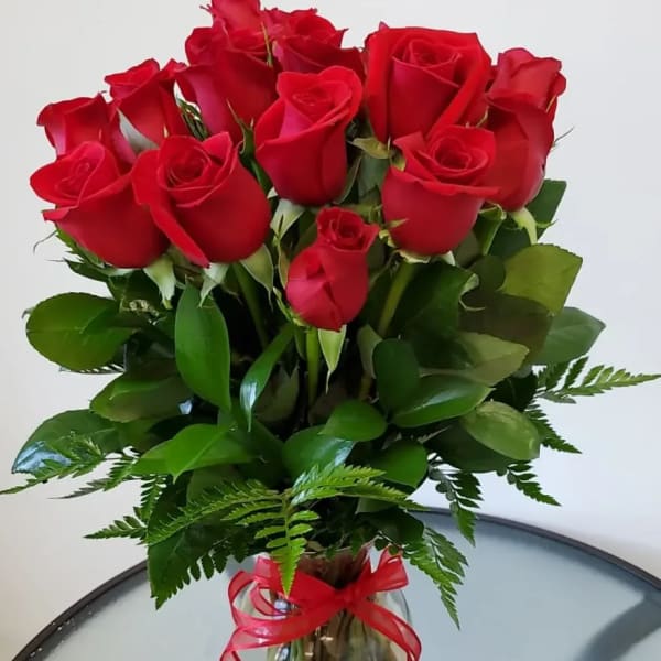 Bouquet of red roses in a clear glass vase with a red ribbon