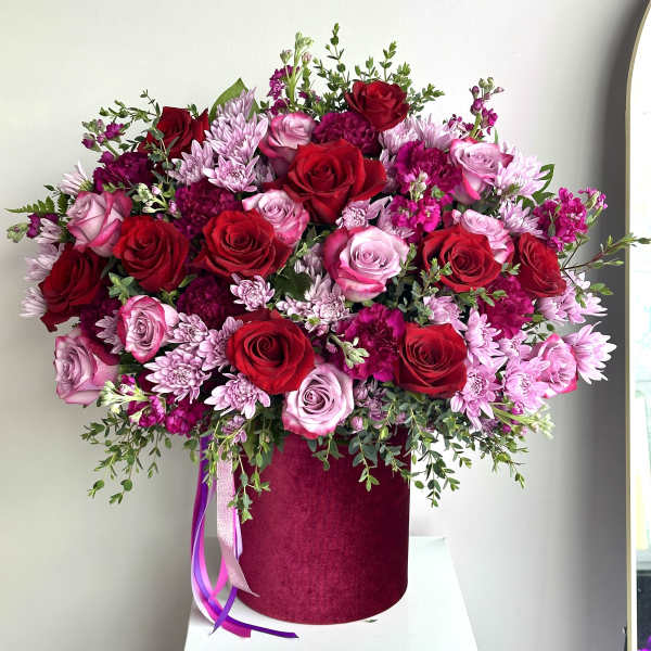 Large pink and red rose arrangement with mums in a deep pink hatbox container