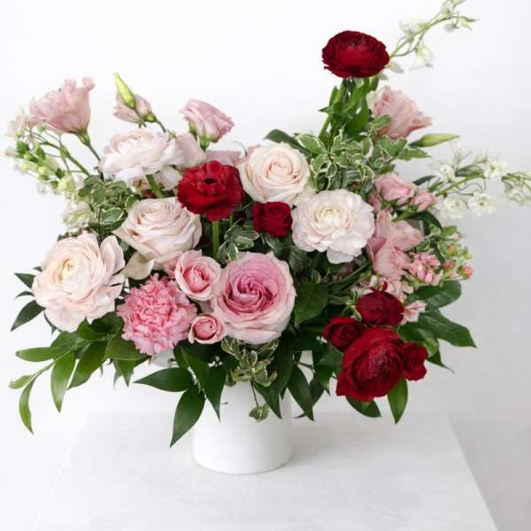 Pink and red rose arrangement in a white vase