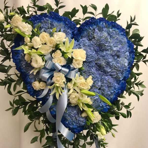 Heart-shaped blue floral tribute with white roses and lilies