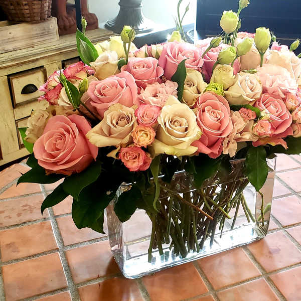 Large bouquet of pink and cream roses in a clear rectangular vase