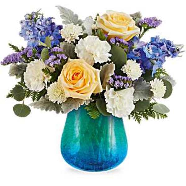 Bouquet of yellow roses, blue hydrangeas, and white carnations in a blue vase