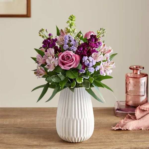 Mixed pink and purple flower arrangement with a rose and alstroemeria in a white ceramic vase