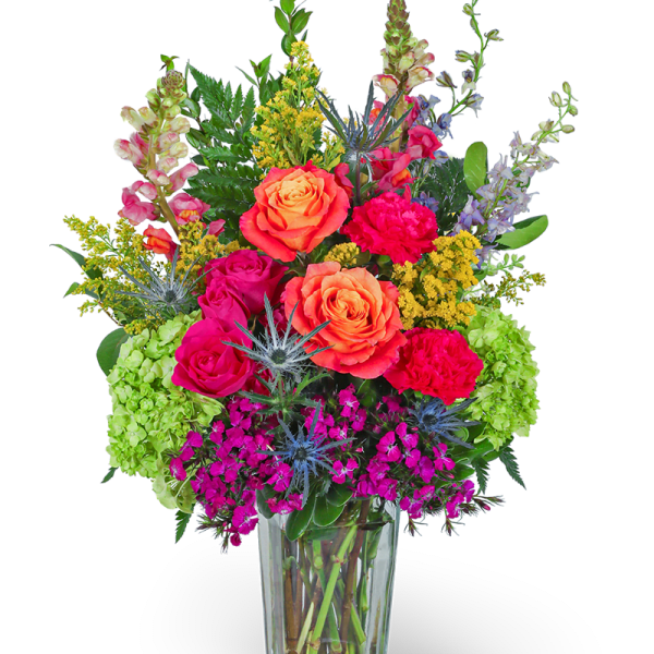 Tall arrangement of bright orange roses, hot pink blooms, and green hydrangeas in a clear glass vase.