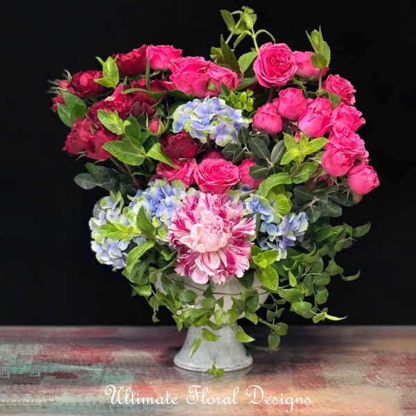 Pink and red roses with blue hydrangeas in a white vase