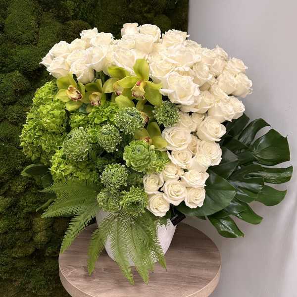 Large arrangement of white roses and green blooms in a white pot