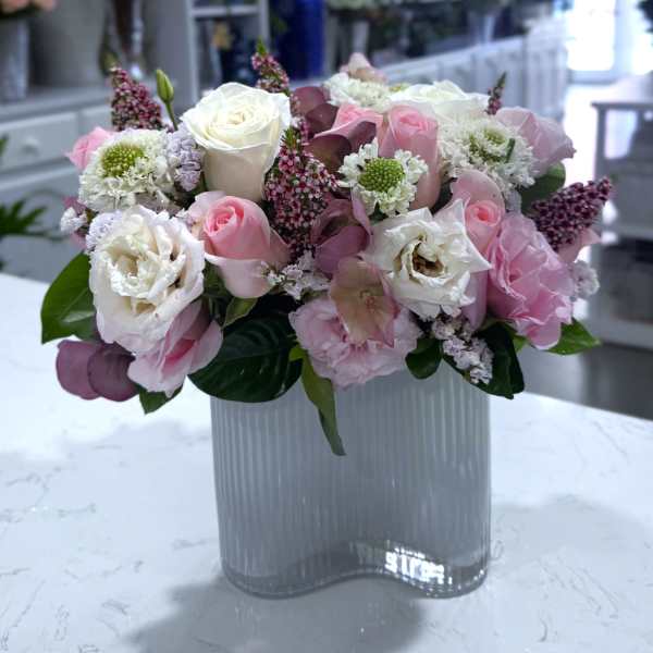 Pink and white rose bouquet in a ribbed glass vase