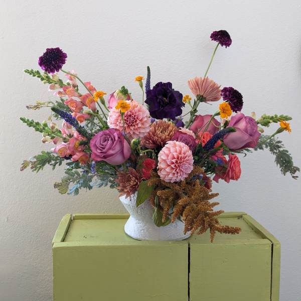 Mixed bouquet in a white vase with pink, purple, and peach flowers