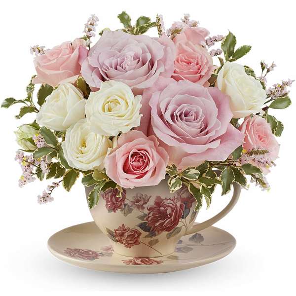 Pink and white roses arranged in a floral teacup with saucer