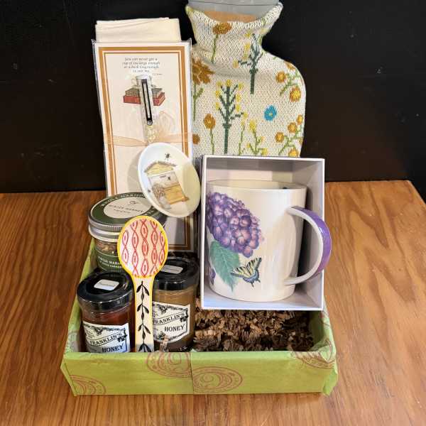 Gift basket with a mug, candles, honey jars, and small accessories