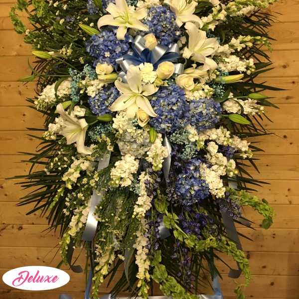Large standing spray of white lilies and blue hydrangeas with ribbon accents
