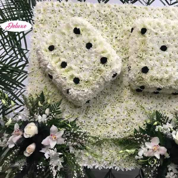 Large white floral funeral tribute with black dot accents and orchid sprays