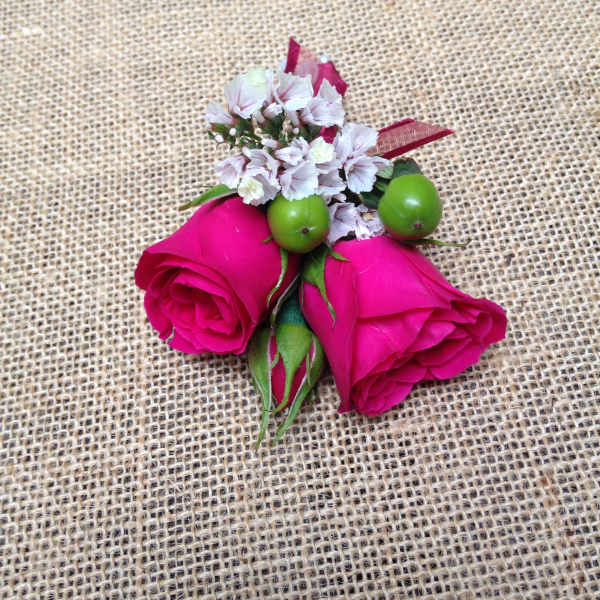 Two pink rose buds with small white filler flowers and green berries