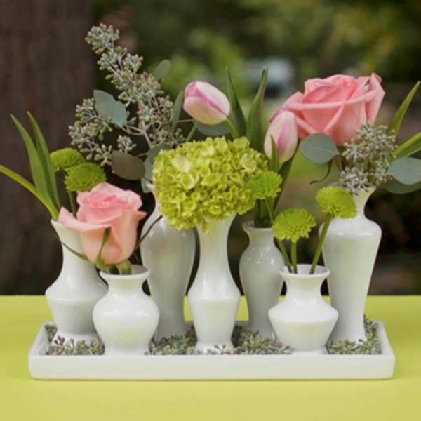 Pink roses and green hydrangea in small white vases on a tray