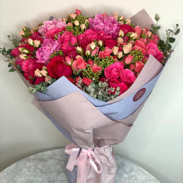 Large bouquet of pink and red roses wrapped in pastel paper
