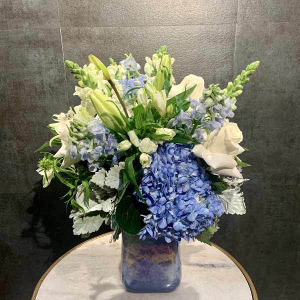 Blue hydrangeas and white lilies in a glass vase