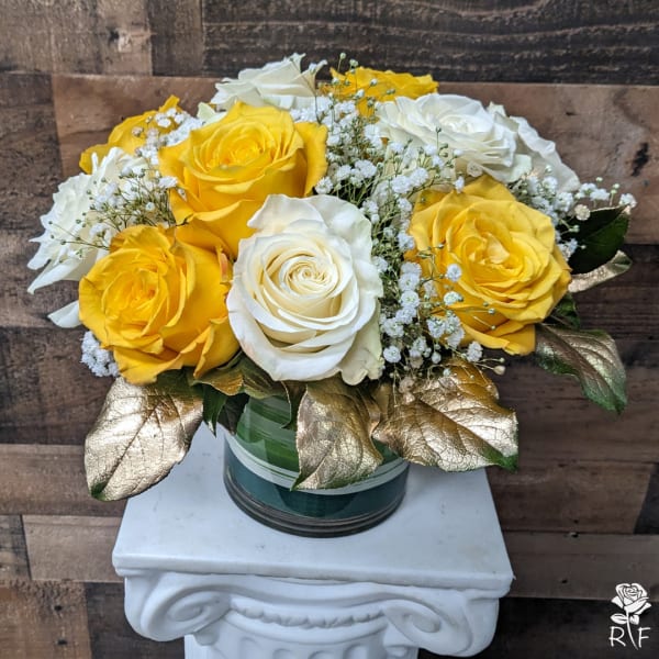 Yellow and white roses in a glass vase with gold leaves