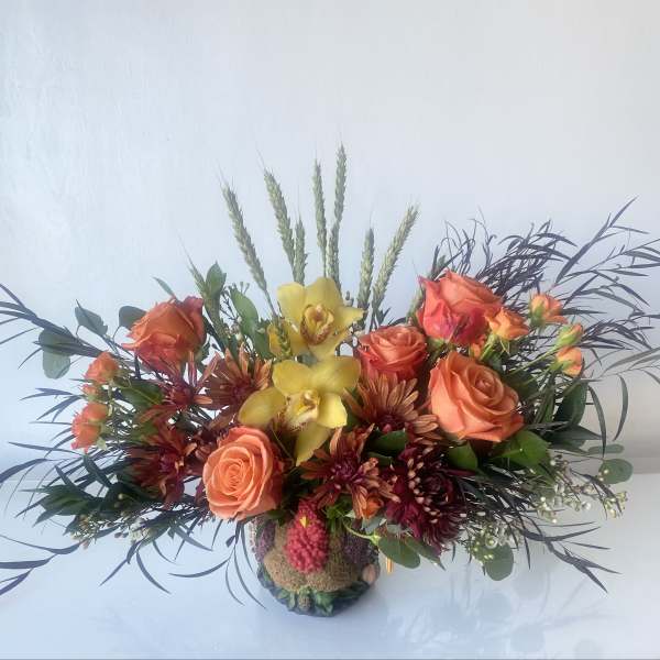 Orange roses and yellow orchids in a low decorative vase