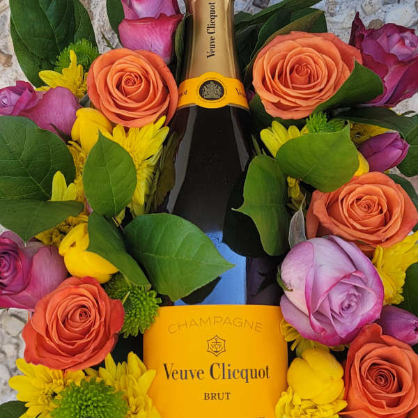 Champagne bottle surrounded by roses and yellow daisies