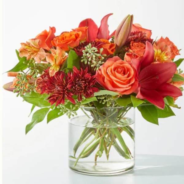 Orange and red mixed bouquet in a clear glass vase